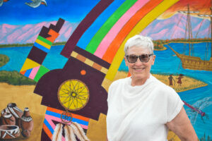 Katy Hammel in front of a painted rainbox.