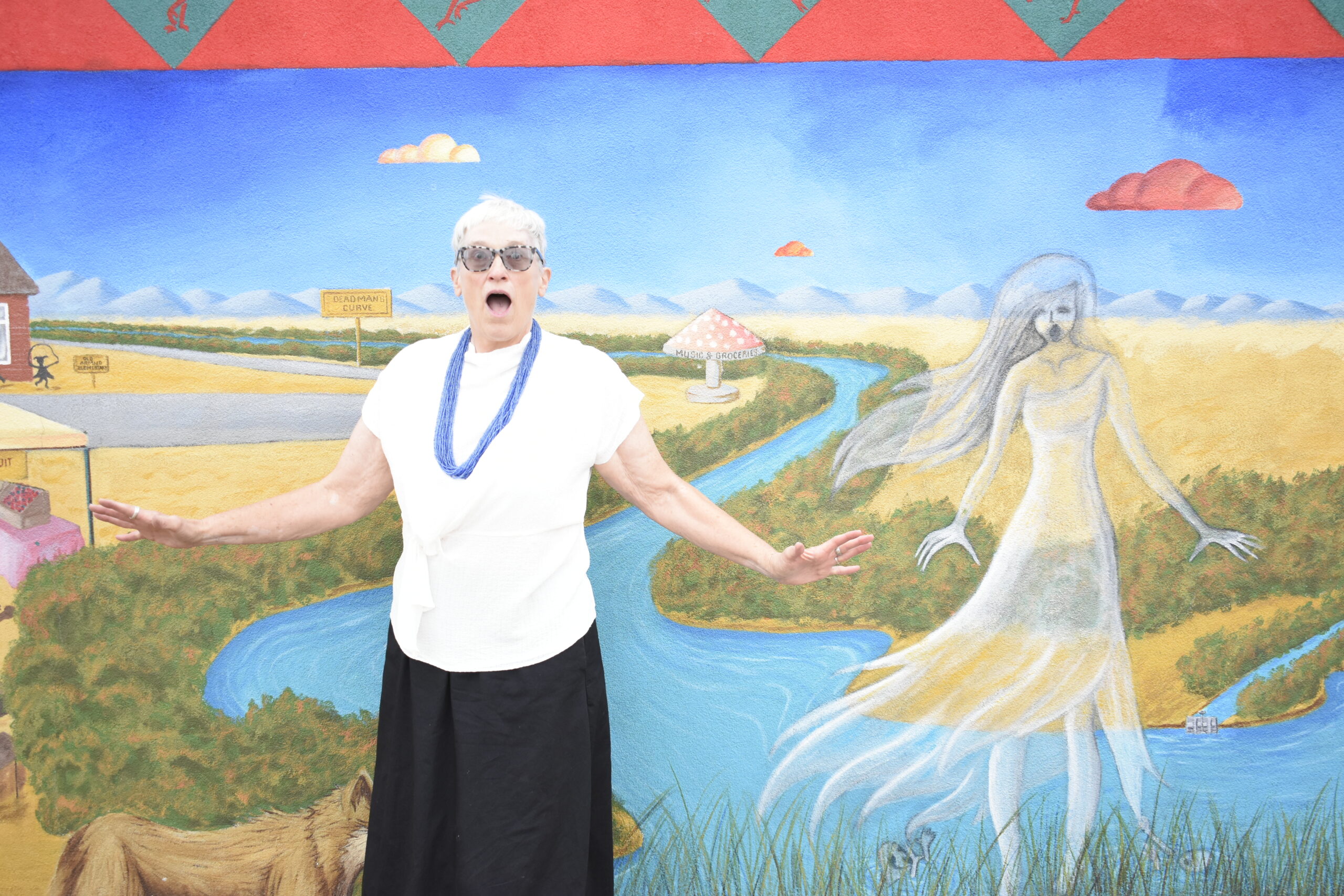 Katy Hammel in front of a painted rainbox.